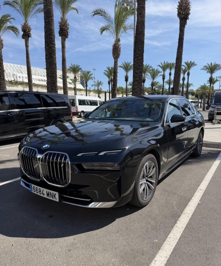 Black BMW i7 parked beneath palm trees.