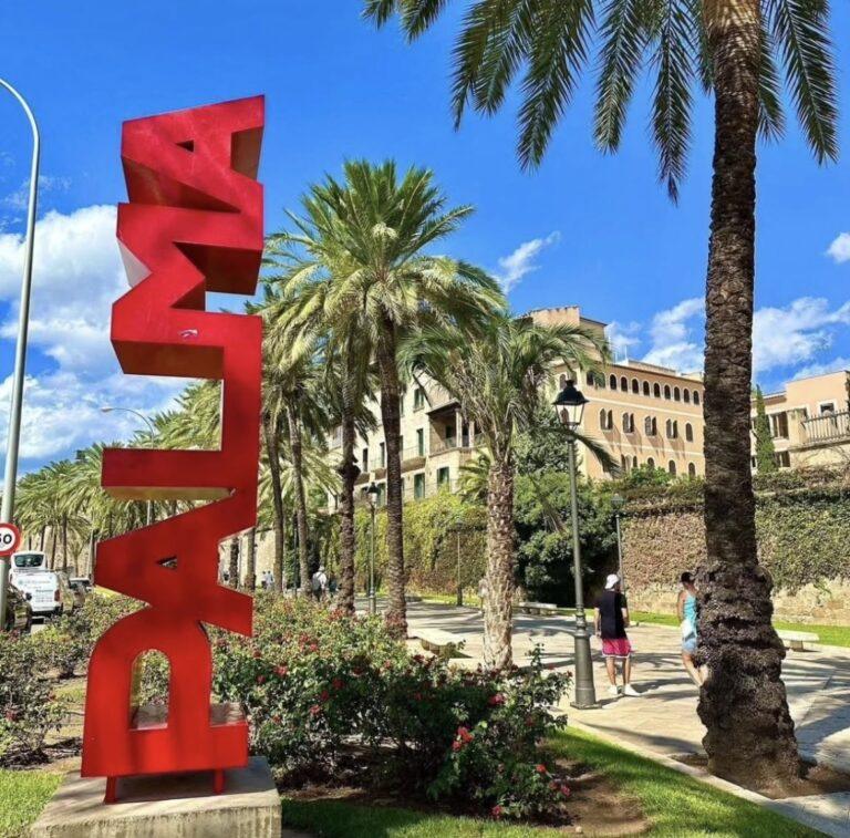 Red Palma sign beside palm trees in Mallorca.