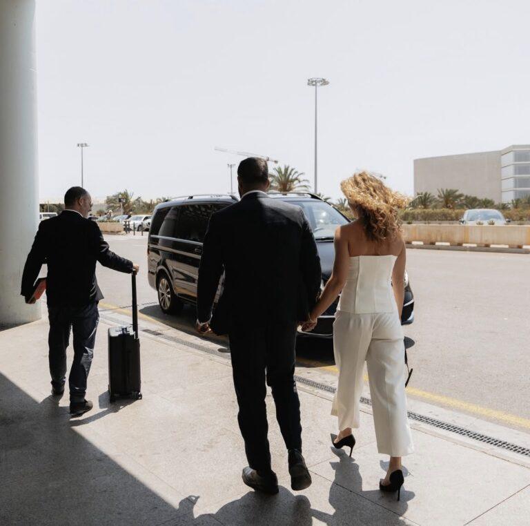 Travellers approaching a black Mercedes-Benz V-Class on an airport apron.
