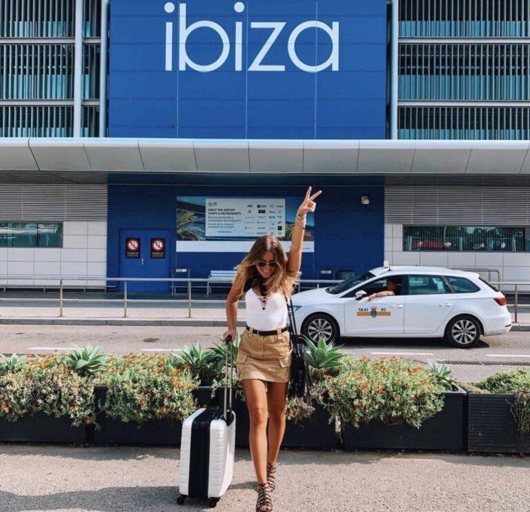 Traveller with luggage outside the Ibiza Airport terminal.