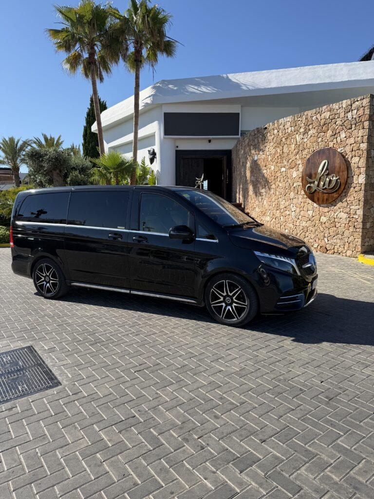 Black Mercedes-Benz V-Class outside a hotel entrance.